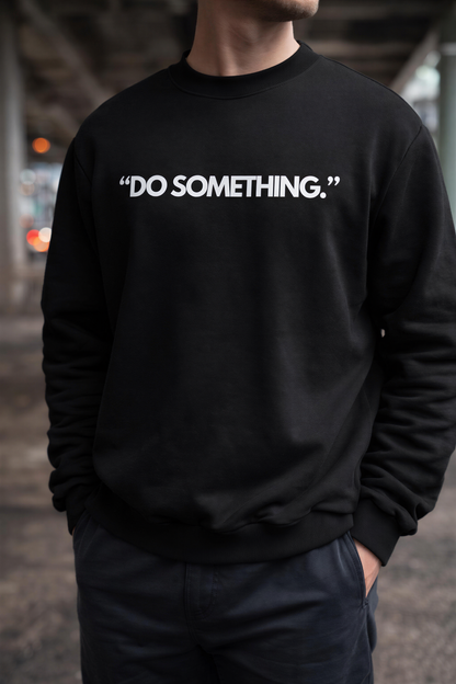 A person wearing a black sweatshirt with the text "DO SOMETHING" printed on it.